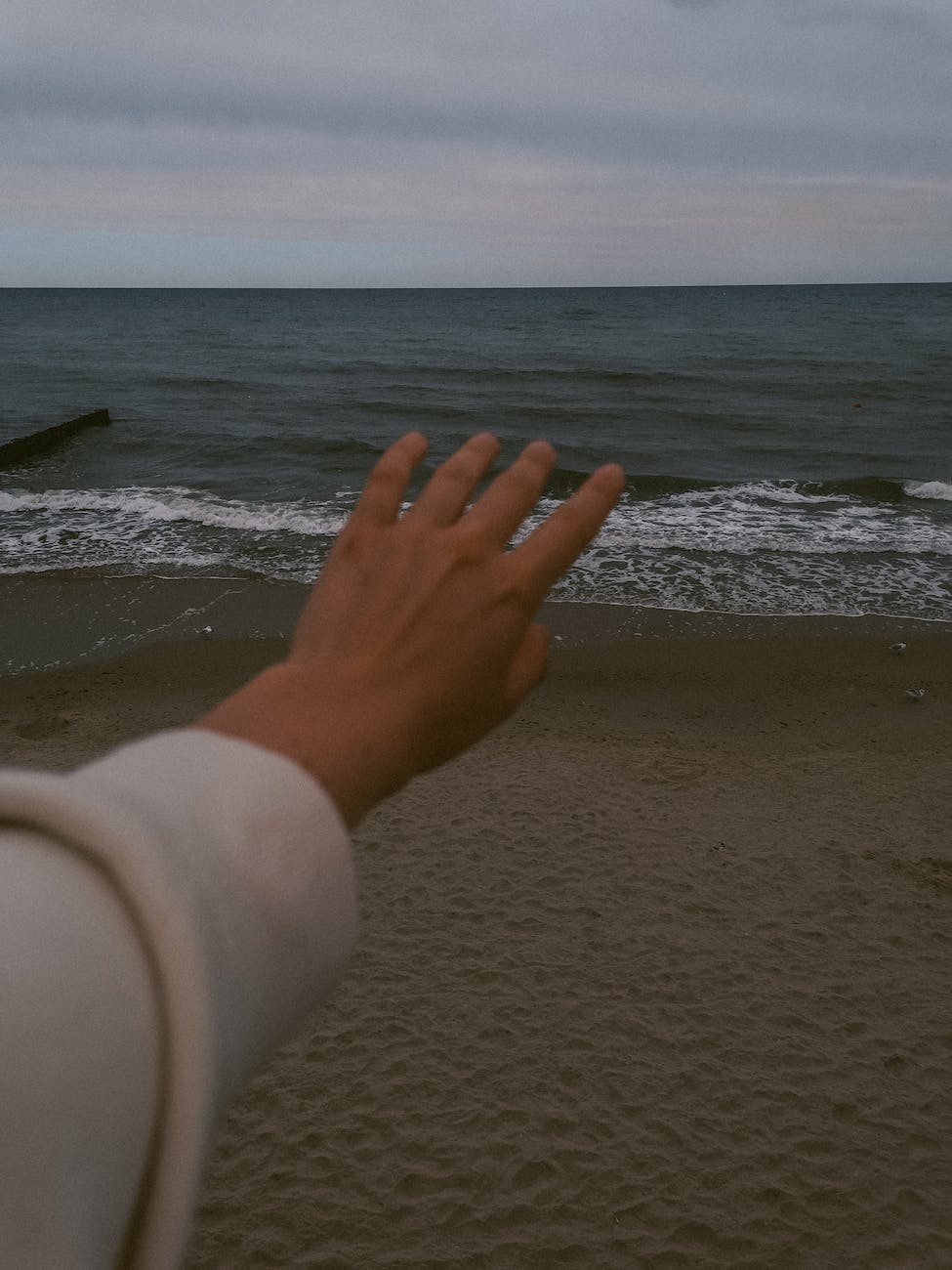 womans hand stretched towards the sea