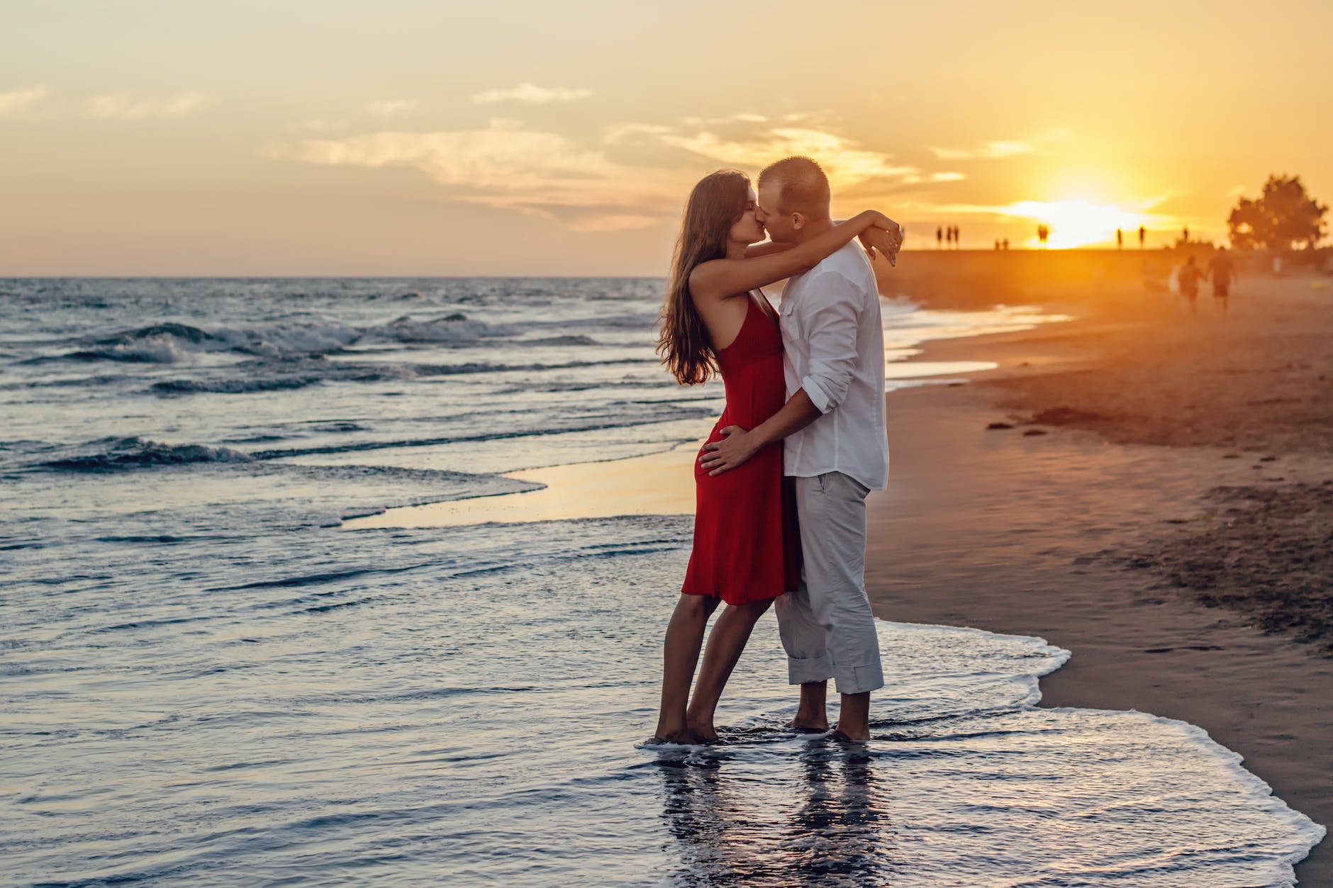 couple kissing on beach during golden hour